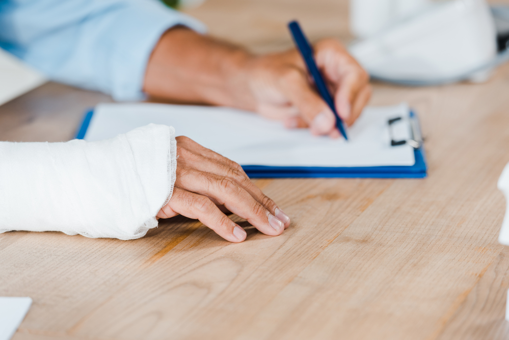 Workers' Compensation Lawyers New York- man writing with cast