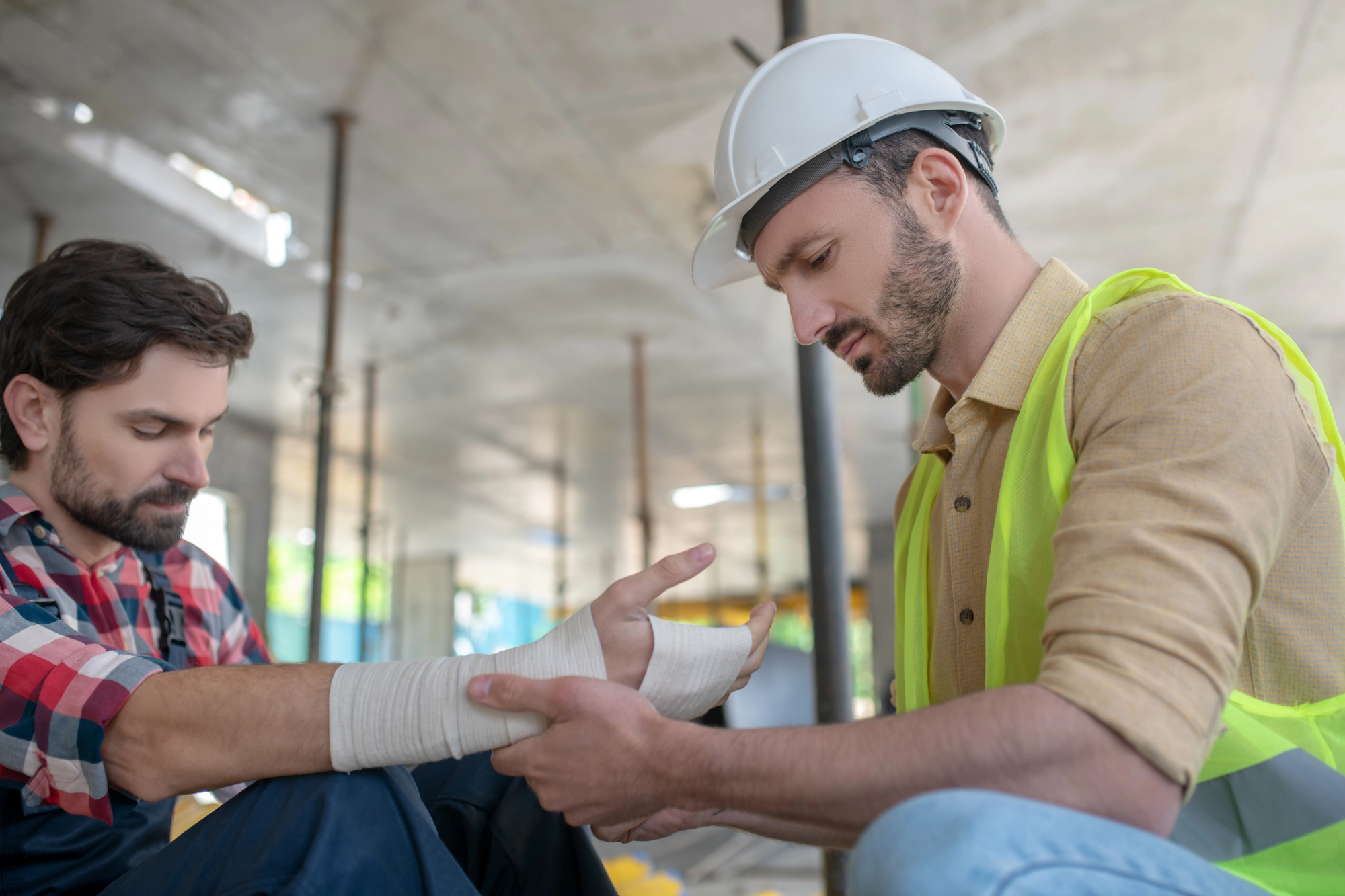 Construction worker wrapping wrist of injured colleague