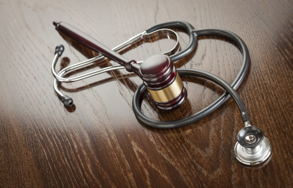 Surgical-Errors-and-Medical-Malpractice- Gavel and Stethoscope on Reflective Wooden Table.