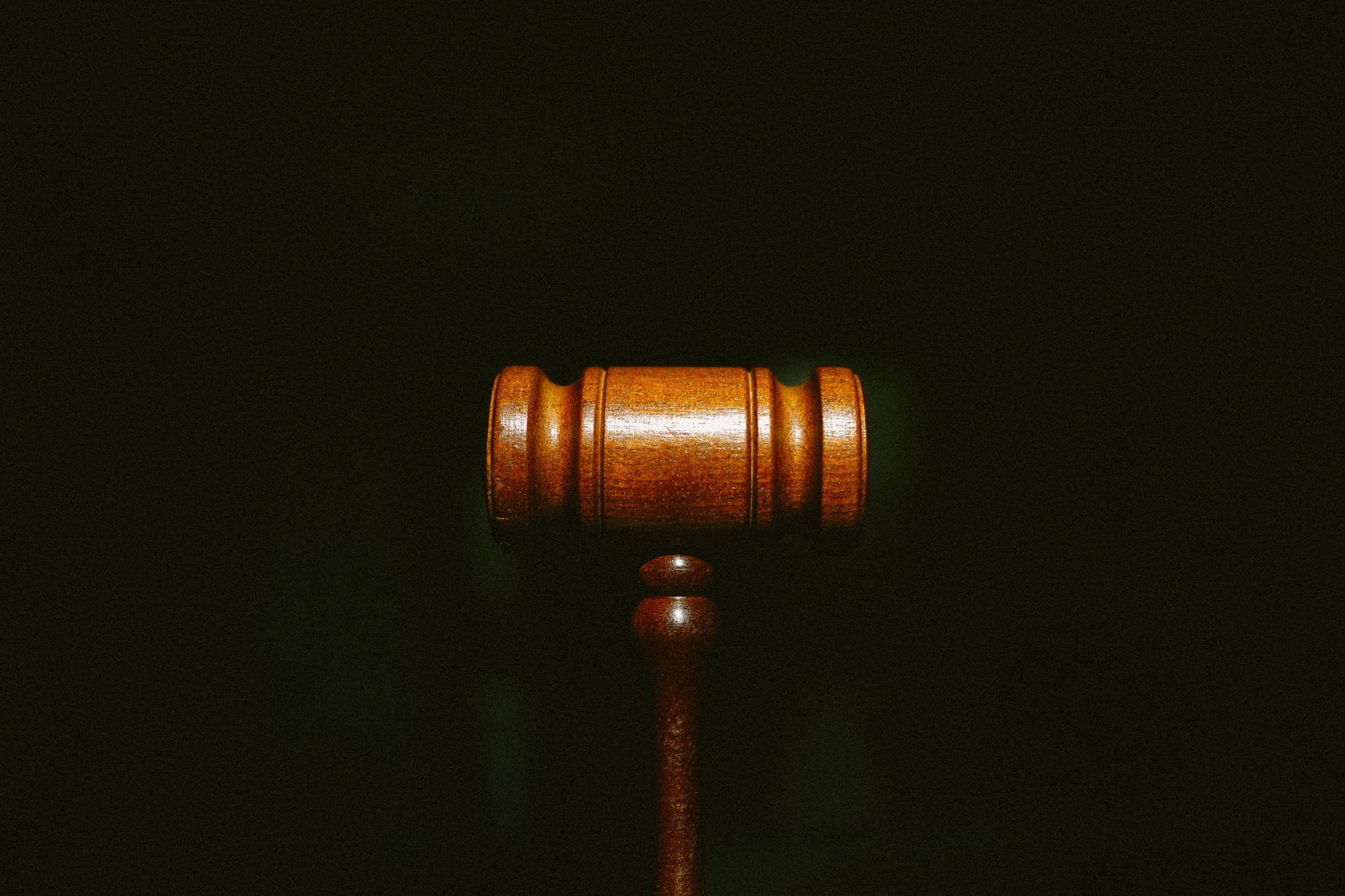 Workers' Compensation Facts - A wooden gavel centered on a dark background with grain.
