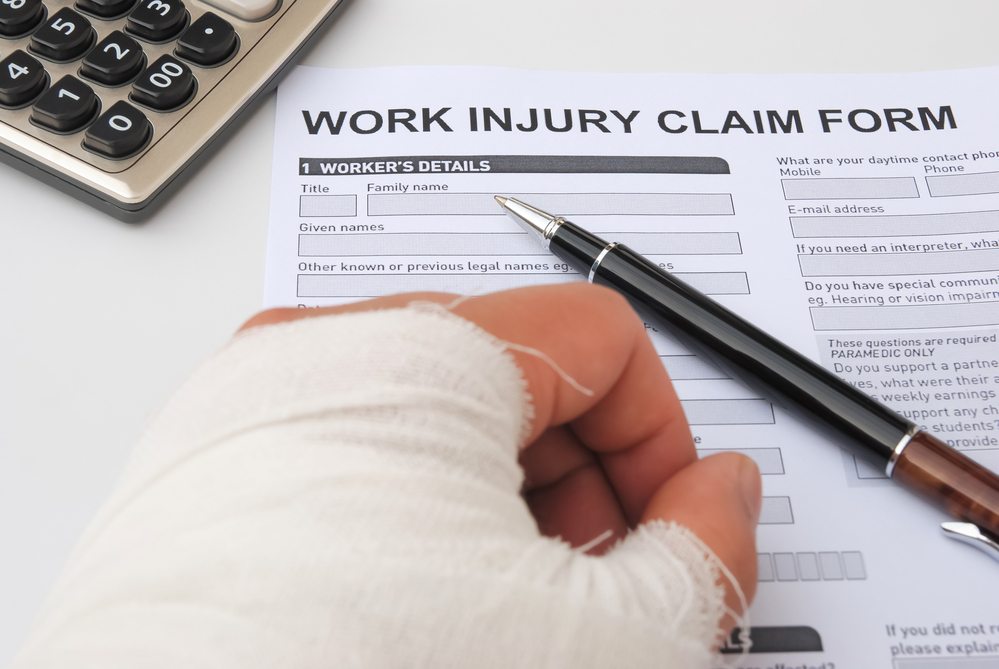 Hurt hand filling out a work injury claim with the help of a New York Workers' Compensation lawyer