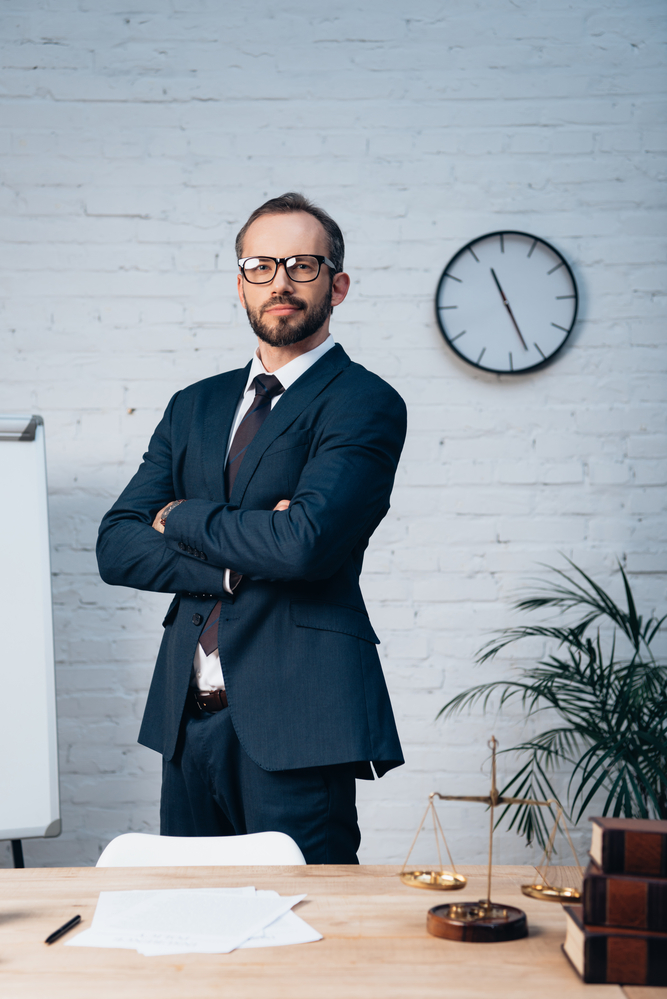 A New York Workers' Compensation lawyer standing at their desk in front of a clock