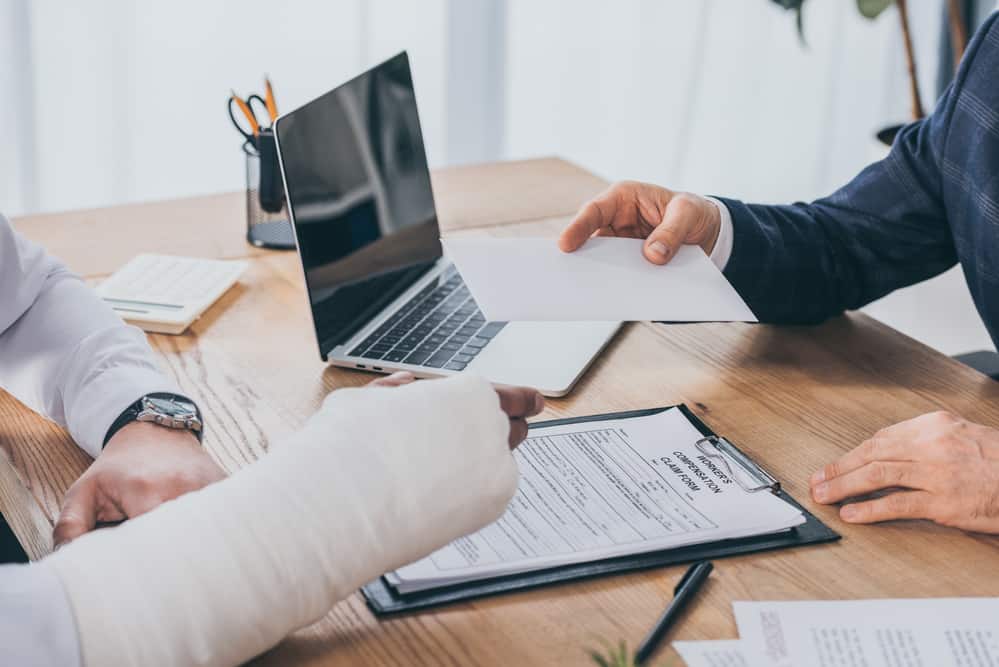 Injured hand filling out paperwork with New York Workers' Compensation lawyer